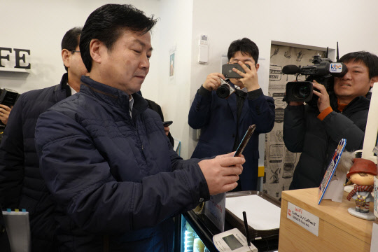 홍종학 중기부 장관이 25일 전남 목포 자유시장 점포를 방문해 '제로페이'로 물품을 구매한 후 스마트폰으로 결제를 진행하고 있다.  중기부 제공
